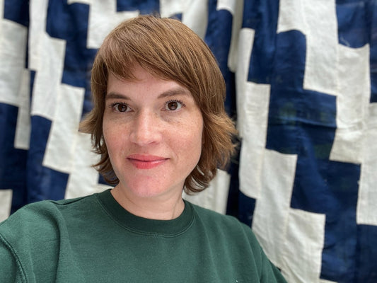 Photo of Amanda with a close up of blue & white quilt behind her